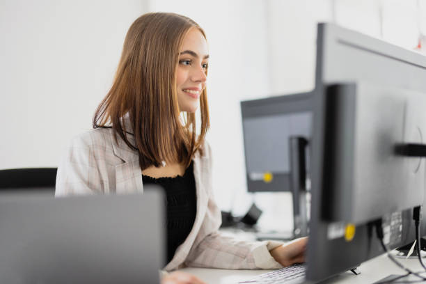 Happy smiling woman in modern office reading e-mails