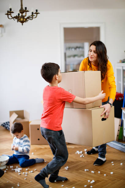 istock Mother carrying stack of boxes, her son is taking one to help her during house move 1284675806