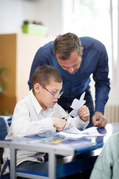 istock Teacher helping special needs boy on his craft skills 1284680988
