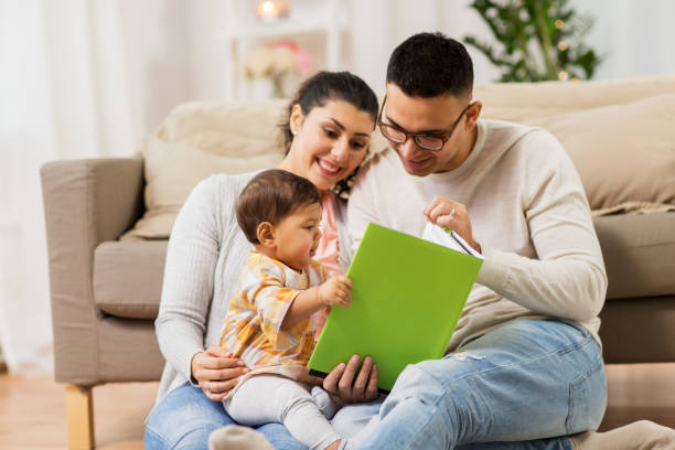 familia feliz con el bebé leyendo libro en casa - child book reading baby fotografías e imágenes de stock