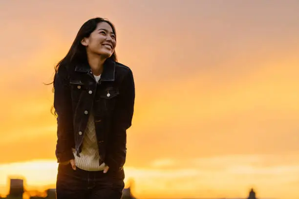 A portrait of a young happy woman in nature during sunset.