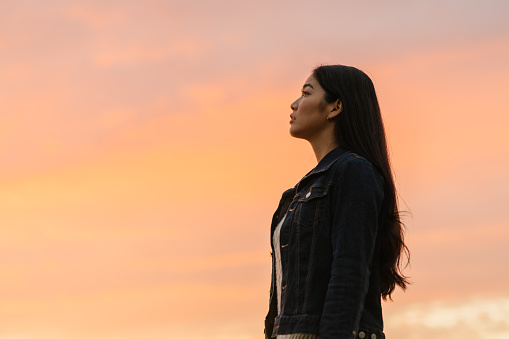 A side view portrait of a young woman in nature during sunset.