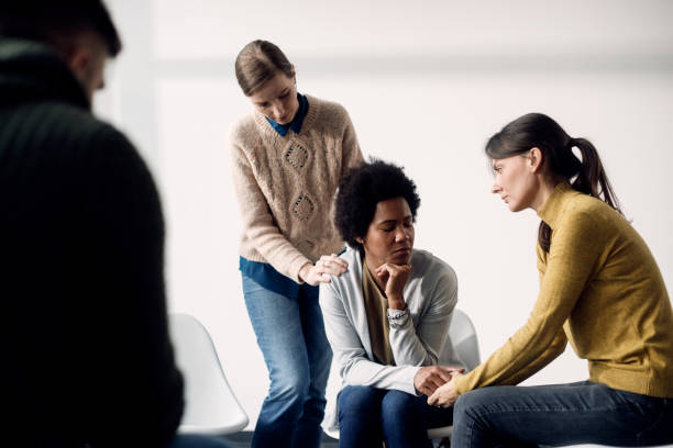 African American woman being consoled by her support group during a therapy. Sad black woman getting support from members of group therapy at community center. nervous holding hands stock pictures, royalty-free photos & images
