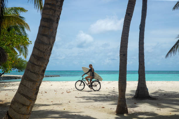 istock Bike ride on the beach with a surfboard 1284685813