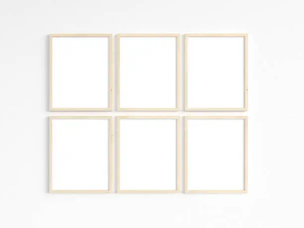 A mockup of six thin 8x10 wooden frames with portrait orientation on a light wall. Vertical frames to display your work. 3D illustration.