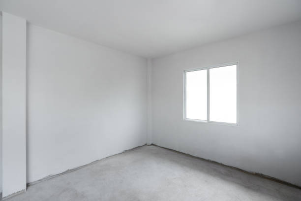 istock Concrete cement floor with white wall and window. Under construction empty room interior 1284687375