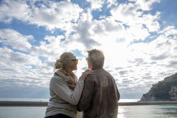 istock Couple relax beside railing, look out to sea 1284687602