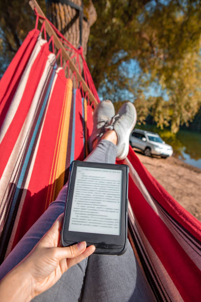 istock woman reading book laying on hammock outdoors at river beach 1284688293