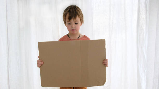 istock Upset boy holds cardboard sheet with space for template 1284688556