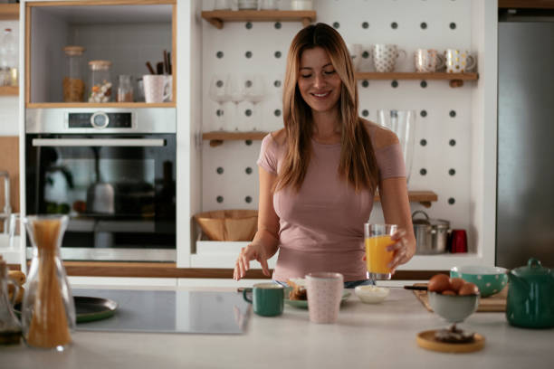 istock Beautiful woman preparing breakfast and drinking juice. 1284690481