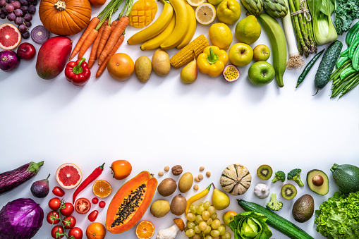 Colorful vegetables and fruits vegan food in rainbow colors arrangement leaving copy space isolated on white