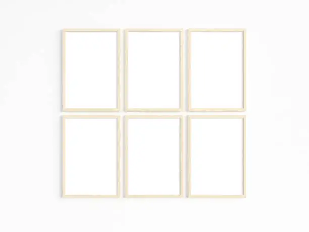 A mockup of six thin A4 wooden frames with portrait orientation on a light wall. Vertical frames to display your work. 3D illustration.