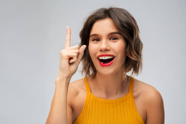 istock happy smiling young woman pointing finger up 1284692087