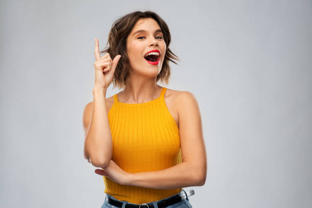 istock happy smiling young woman pointing finger up 1284692898