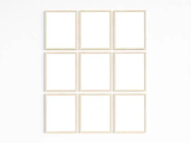 A mockup of nine thin 8x10 wooden frames with portrait orientation on a light wall. Vertical frames to display your work. 3D illustration.