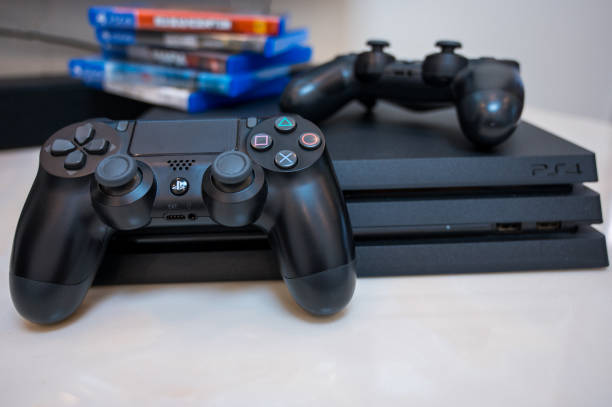 Sony Play Station 4 Pro gaming console on the table with two joysticks and some  games on DVD for PS4. Chengdu, Sichuan province, China - November 26, 2019: Digital gaming console Sony Playstation 4 Pro brand name games console stock pictures, royalty-free photos & images