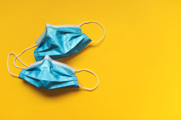 istock Virus mask on yellow background 1284696615