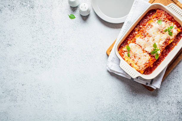 canelones tradicionales con ricotta y espinacas en salsa de tomate en plato de cerámica, vista superior. concepto de comida italiana. - lasaña fotografías e imágenes de stock