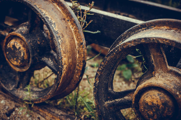 close up of an old wagon wheel made of wood with iron casing, weathered rotten wood rusted iron, a second one as silhouette in the back