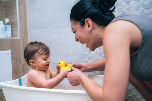Mother and her little son in bathroom playing and bathing