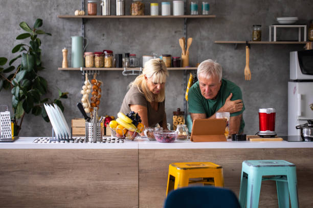 istock Senior couple searching for recipe on digital tablet while preparing smoothie 1284699522