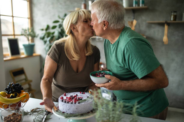 istock Senior couple kissing while decoration cake together in modern kitchen 1284699775