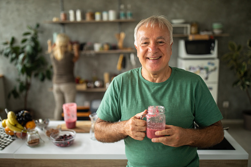 Portrait of senior man at home with freshly made smoothie