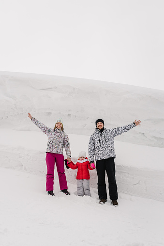 Portrait of happy family walking in a snow mountain in winter. Father, mother and children daughter are having fun and playing on snowy winter in park.