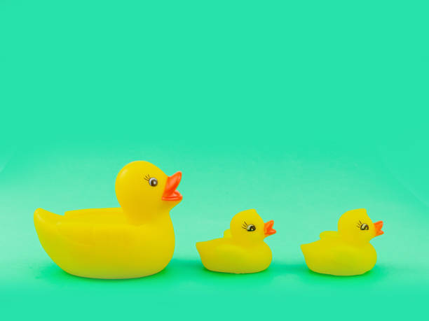 istock Yellow Rubber Ducks Mom and Childs Figures on Green Background 1284711949