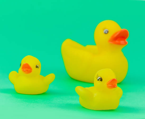 istock Yellow Rubber Ducks Mom and Childs Figures on Green Background 1284712007