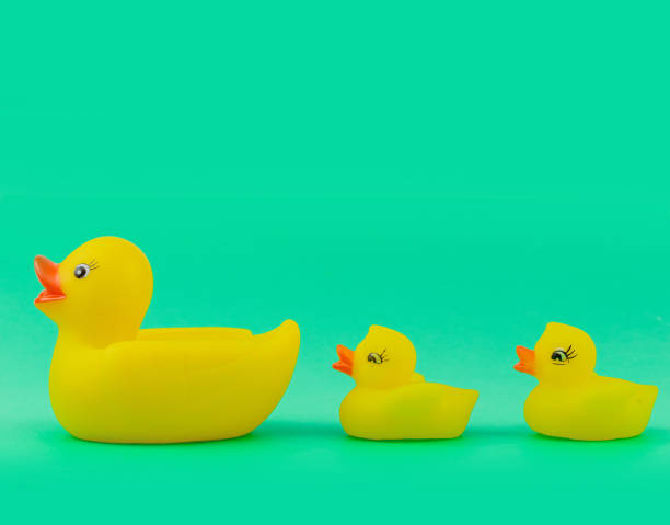istock Yellow Rubber Ducks Mom and Childs Figures on Green Background 1284712010