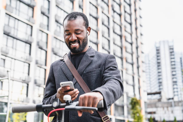 istock Happy afro 30s man checking his phone during e-scooter ride in big city 1284712098