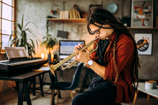 istock Young hipster musician with dreadlocks playing trumpet in music studio 1284715229