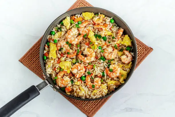 Shrimp Fried Rice in a Skillet on a Place Mat Top Down Flat Lay Photo on White Background
