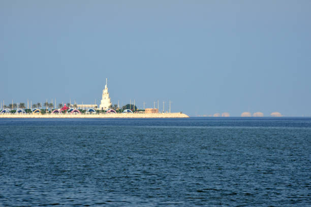 Dammam, Eastern Province, Saudi Arabia: Al Murjan Island with oil industry facilities in the background - an artificial island on the corniche, featuring a park with covered picnic areas, ferry-boat rides & a playground - spiral tower like the minaret of the Great Mosque of Samarra - Persian Gulf, Al-Hamra'a