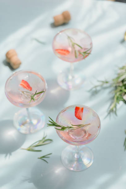 istock Summer drink with white sparkling wine. Homemade refreshing fruit cocktail or punch with champagne, strawberries, ice cubes and rosemary on light blue background. 1284718620