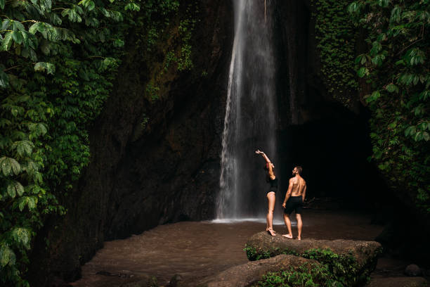 Beautiful couple at the waterfall. A couple in love travels to Indonesia on the island of Bali. A man and a woman at a waterfall in Indonesia. Vacation in Bali. Honeymoon trip. Copy space stock photo