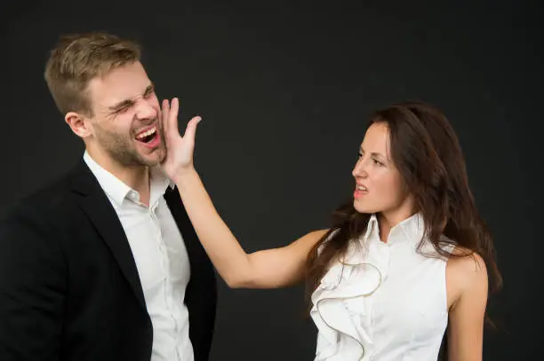 Photo of Abuse at work. Angry woman slap man in face. Using physical abuse in workplace. Physical harm. Coworker harassment and discrimination. Bullying and violence. Occupational injury. Victim protection