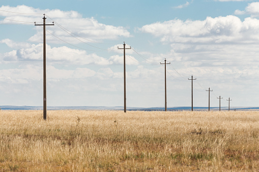Two electricity poles, a wooden and a concrete one with electrical wires, selective focus