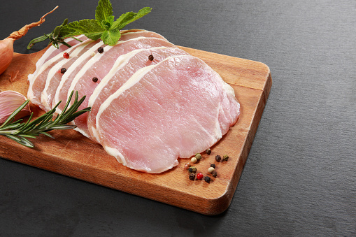 Dry pork meat with rosemary, served on a wooden cutting board, on a home, bar or restaurant table, a close up image with a copy space, macro image