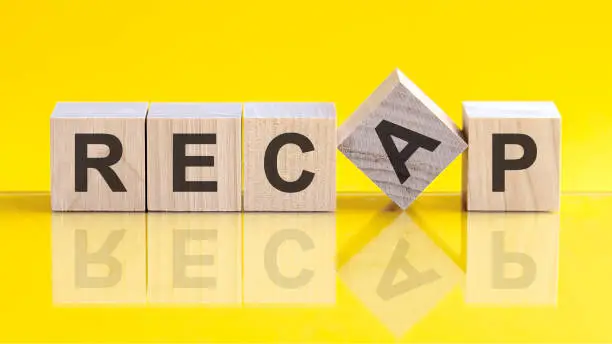 recap word written on wood block. recap word is made of wooden building blocks lying on the yellow table. recap, business concept, yellow background