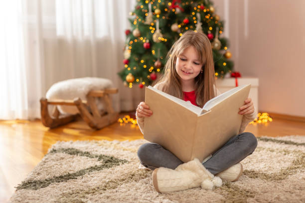 istock Little girl reading a book by the Christmas tree 1284727149