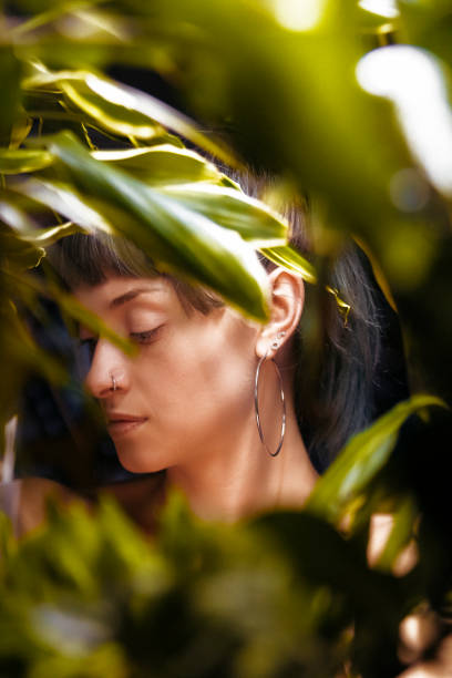 jeune belle femme avec des usines tropicales. beauté naturelle, portrait de jeune femme attrayant tout en restant parmi les feuilles, collage avec le portrait féminin. femme avec le maquillage naturel et les feuilles vertes, belle femme derrière des feu - beautiful boredom sensuality desire photos et images de collection