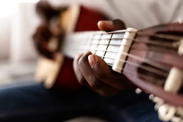 Photo of Young contemporary male musician in casualwear playing acoustic guitar