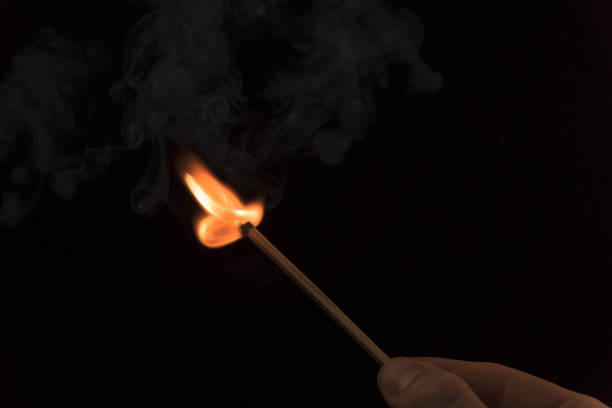 istock A lighted match on a black background. Hold a lighted match. The fire from the match illuminates everything around. Arson, danger, flash. Macro fire burning on matchstick. Idea, concept, 1284729140
