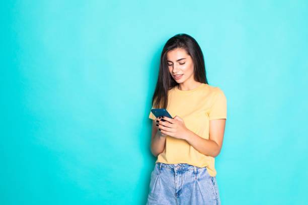 istock Young woman use phone isolated on turquoise background 1284732656