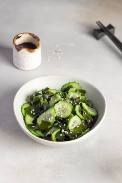 Japanese Sunomono salad with wakame seaweed and cucumber in bowl Japanese Sunomono salad with wakame seaweed and cucumber in bowl. Asian food. Gray background. vertical image sunomono stock pictures, royalty-free photos & images