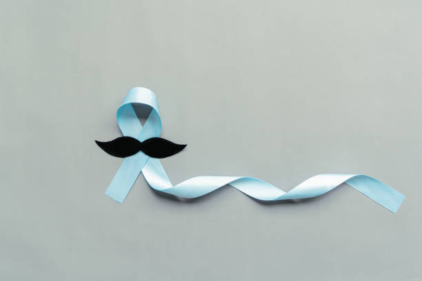 istock November light blue ribbon with mustache on gray background with copy space, Prostate cancer awareness month, men's health concept 1284735651