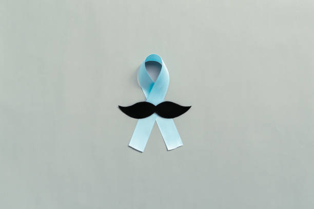 istock November light blue ribbon with mustache on gray background with copy space, Prostate cancer awareness month, men's health concept 1284735696