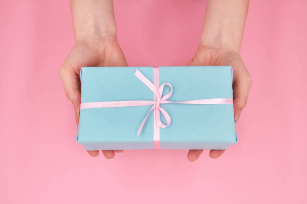 istock A woman holding in hands Christmas or New Year gift box against a pink background 1284735708